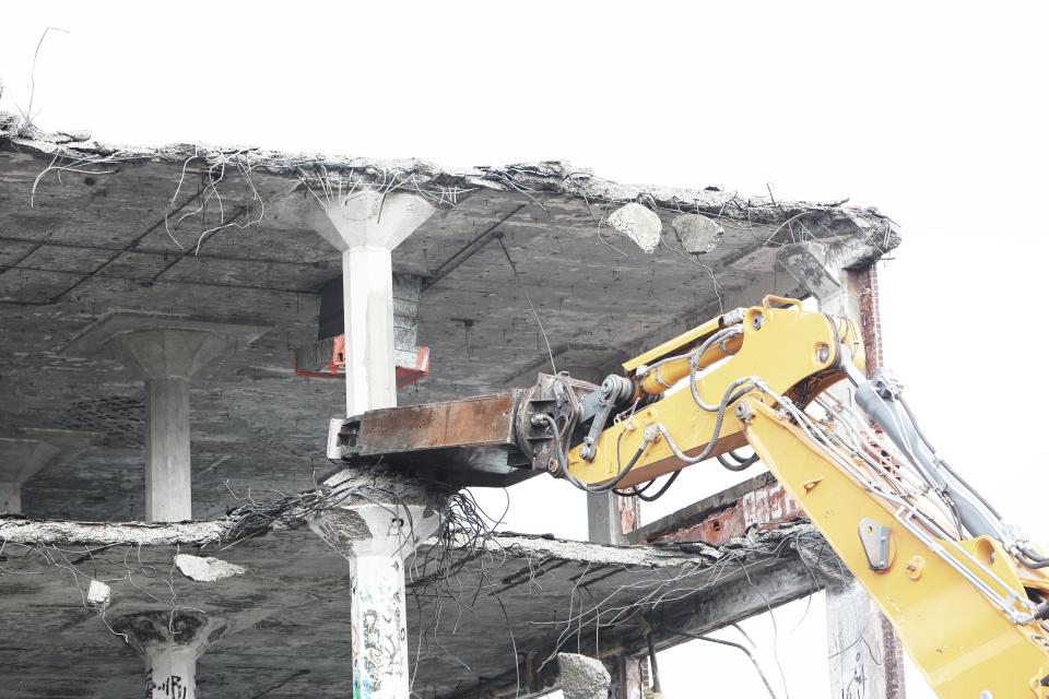 Pelle mécanique effectuant la démolition d'un bâtiment de béton à Shawinigan